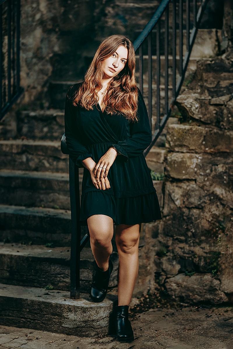 Frau im schwarzen Kleid auf einer alten Steintreppe